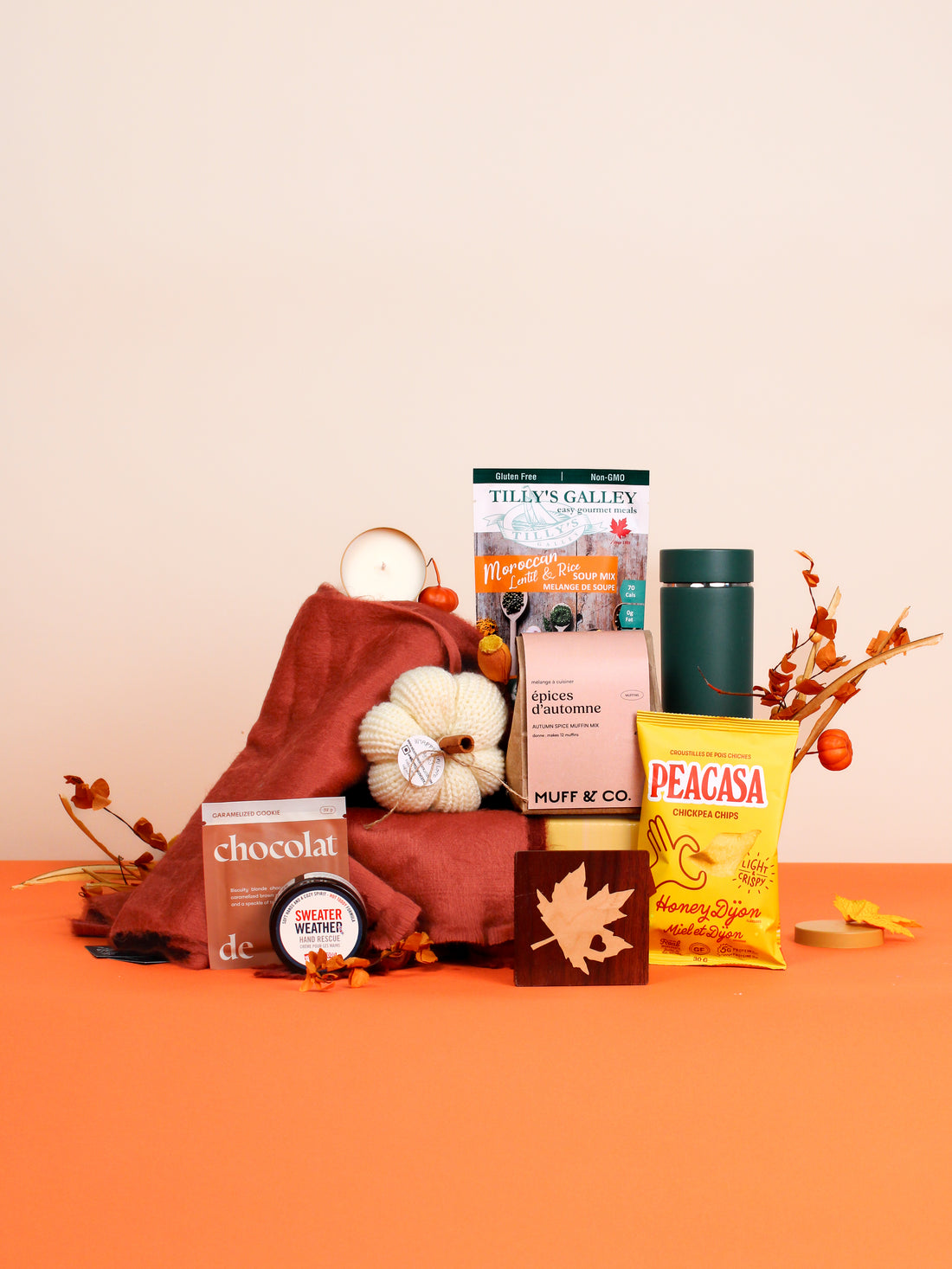 Beautifully arranged Fall Cozy Box gift set featuring artisan chocolate, pumpkin spice muffin mix, scarf, hand cream, tea tumbler, candle, and seasonal snacks—perfect for autumn gifting.